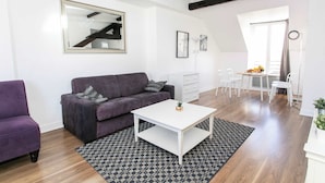 A modern living room with a sofa, a coffee table, and a patterned rug. - Le Marais - 1BR by Pompidou (Paris)