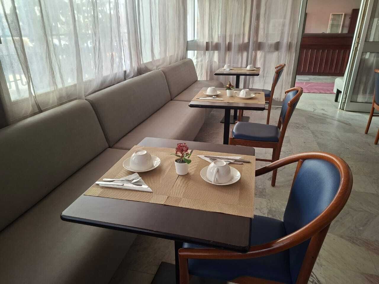 Een eetgedeelte met een bank, tafels, stoelen en een kleine plant in pot.