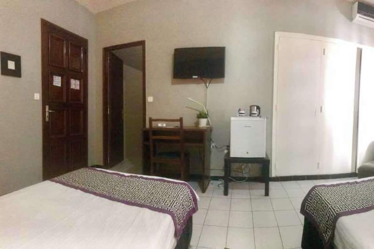 Ett hotellrum med två sängar, ett skrivbord med en dator, en tv, en garderob och en stol.