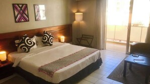 A hotel room with a bed, bedside lamps, a chair, and a view of the outside. - hotel BARAKA (Dakar)