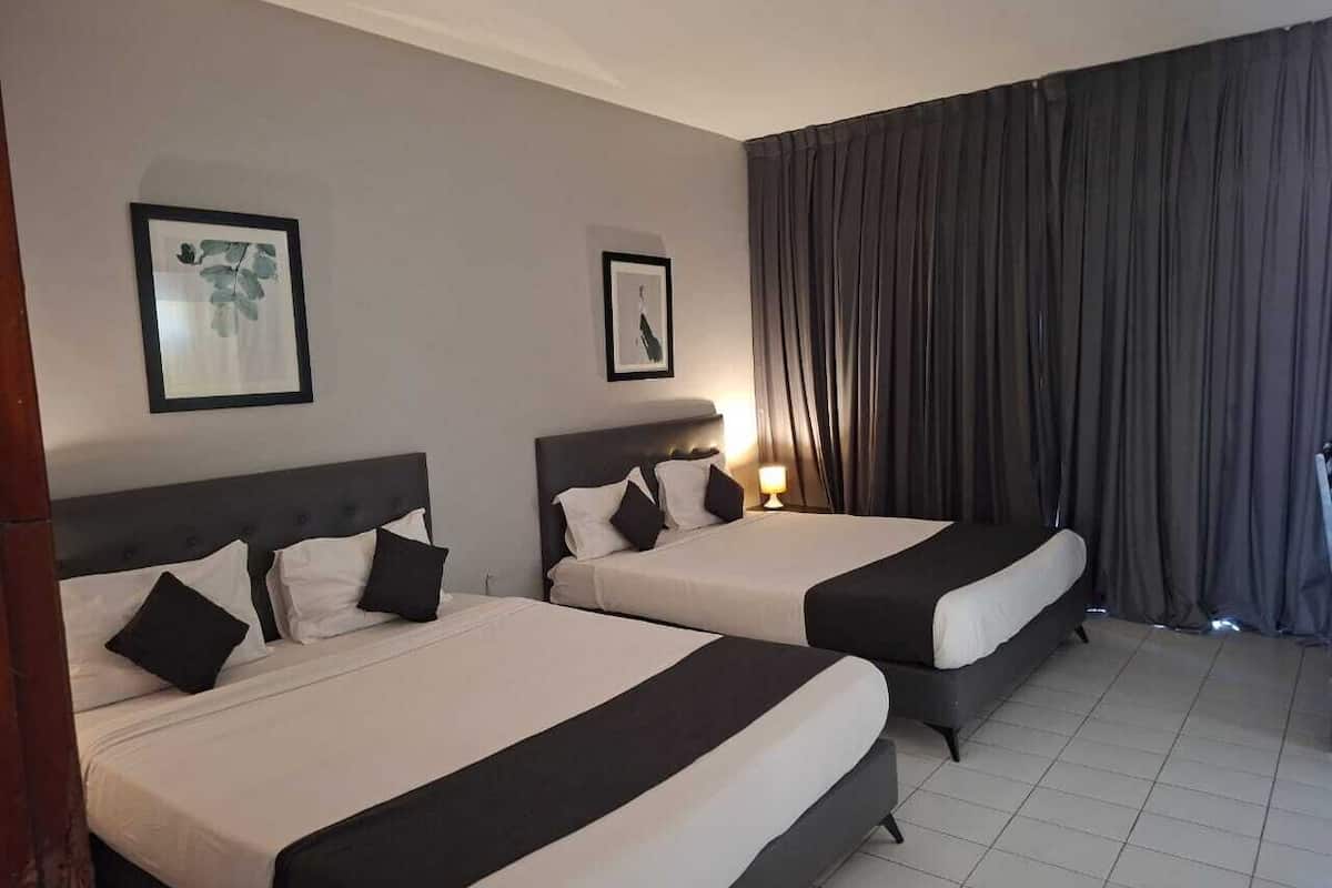 Une chambre d’hôtel avec deux lits, chacun doté d’une literie noire et blanche, d’une tête de lit et d’un tableau encadré au mur.