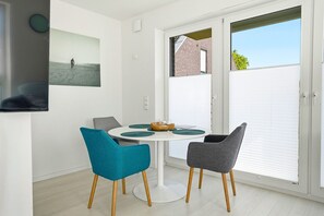 A dining area with a round table, two chairs, and a picture on the wall. - Family & friends - Holiday apartment family & friends: balcony, elevator & great (Norden)
