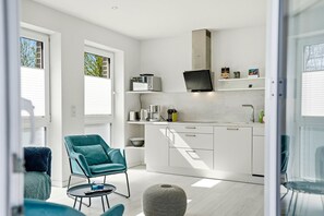 A modern kitchen with white cabinets, a built-in microwave, and a large window. - Family & friends - Holiday apartment family & friends: balcony, elevator & great (Norden)