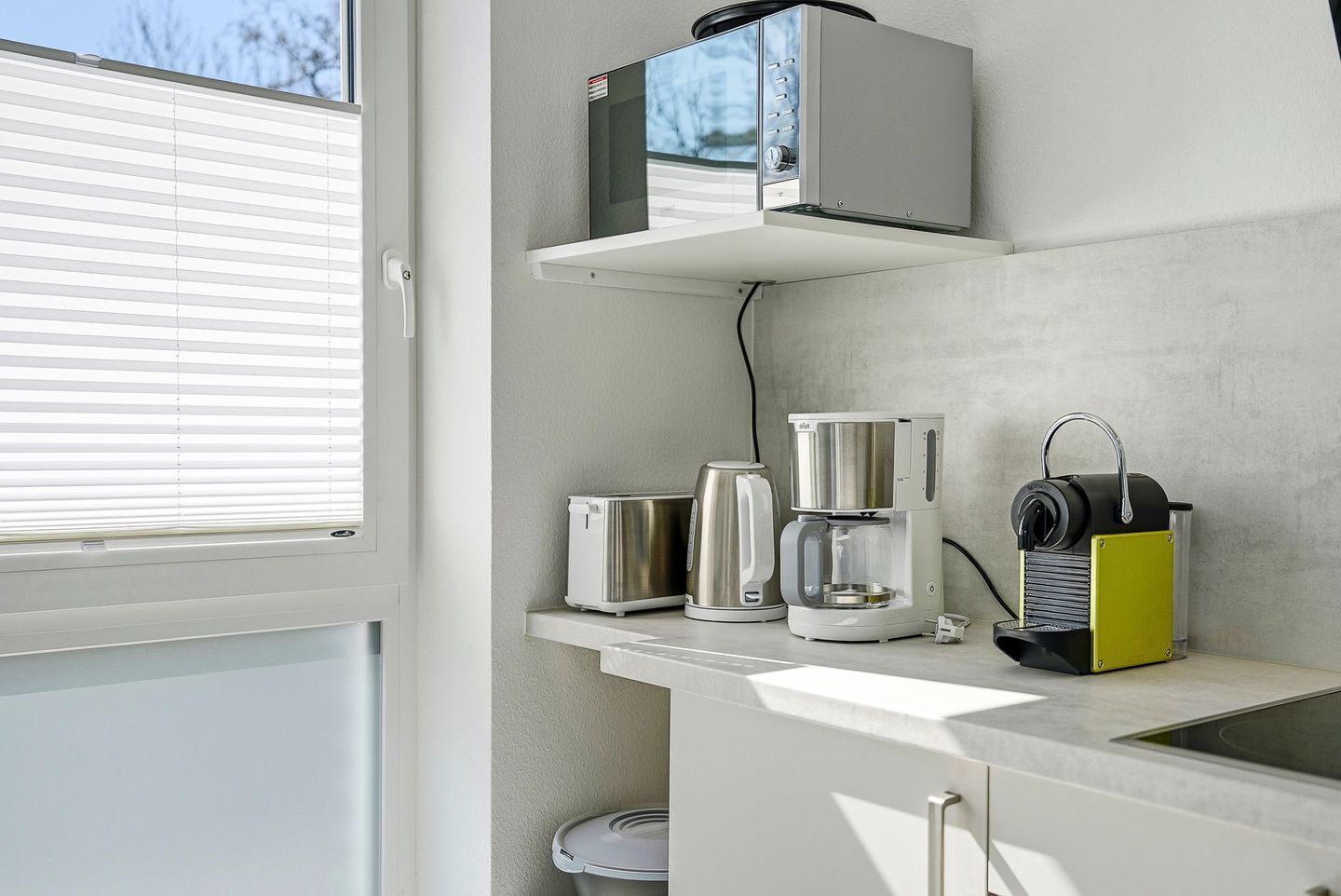 A kitchen with a coffee maker, a toaster, and a microwave on a countertop.