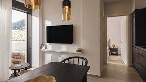 Un'area pranzo moderna con un tavolo in legno scuro, sedie nere e un'ampia finestra che mostra una vista su un edificio con tetto in tegole.