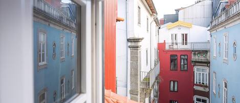 A narrow street with colorful buildings, a visible window, and a red-tiled roof.