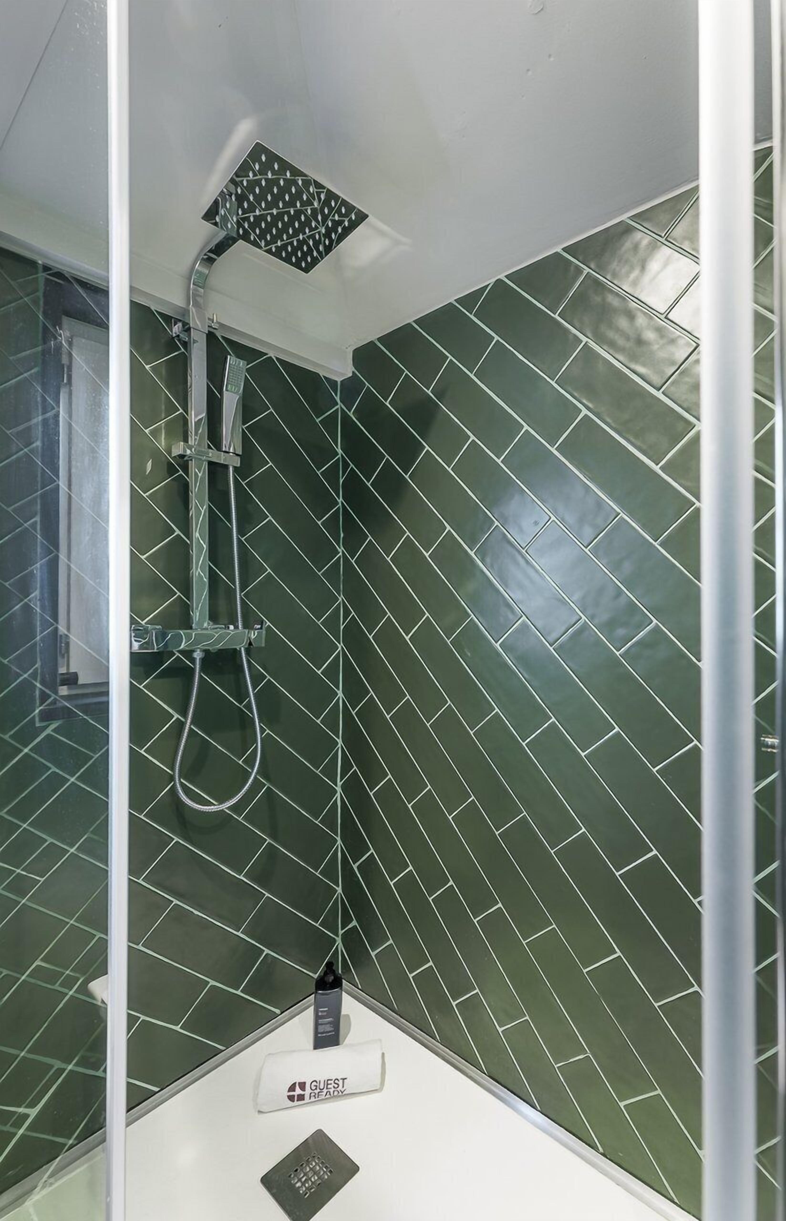 A shower with a handheld showerhead and a wall-mounted control panel.