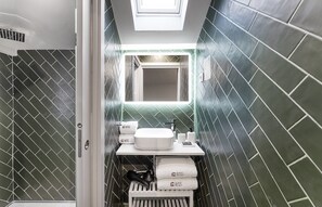 A compact bathroom with a modern design, featuring a white sink, a mirror, and a towel rack with towels. - Guestready - The Cats Studios (Porto)