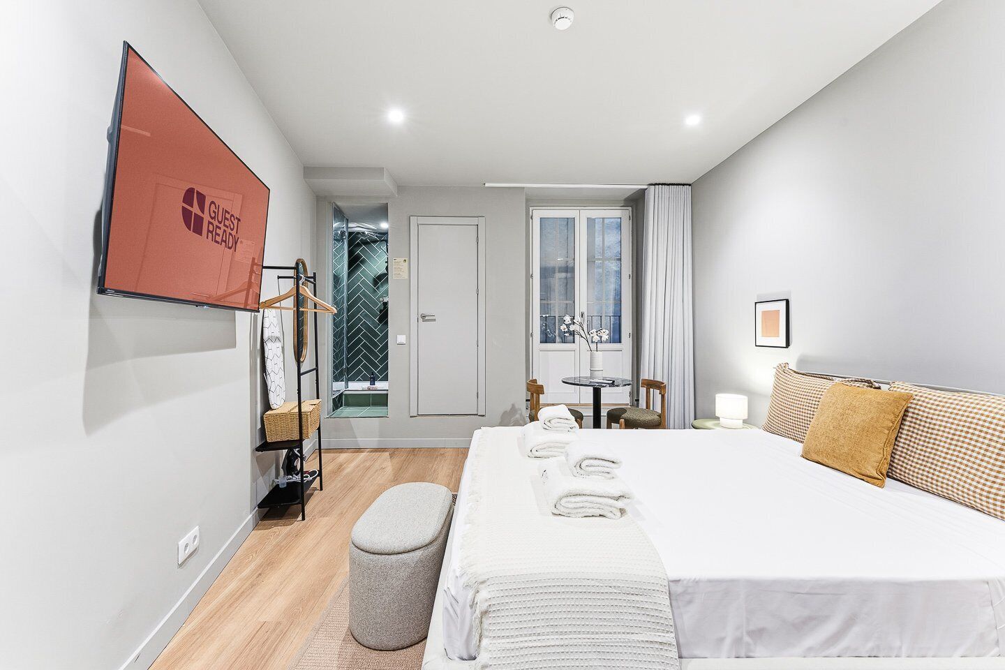 A modern hotel room with a large bed, a bedside table, a chair, and a window with curtains.