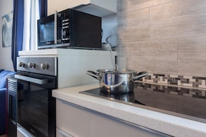 A kitchen with a microwave, oven, and a pot on the stove. - GuestHost - Relax & Fun Home between sea & city (Sinnai)