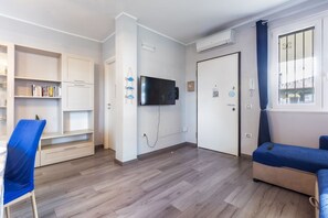 A modern living room with a flat-screen TV, a sofa, a chair, and built-in shelving. - GuestHost - Relax & Fun Home between sea & city (Sinnai)