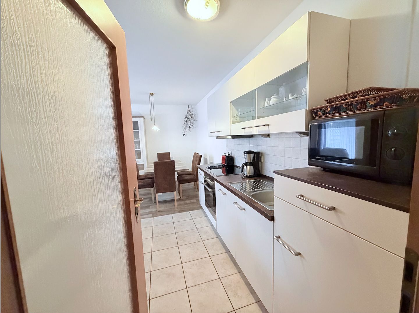 Una cocina moderna con armarios blancos, un microondas y una cafetera.