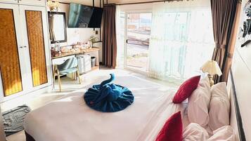 Ein Hotelzimmer mit einem großen Bett, einem Schreibtisch, einem Sessel, einer Kandelaber und Blick ins Freie.