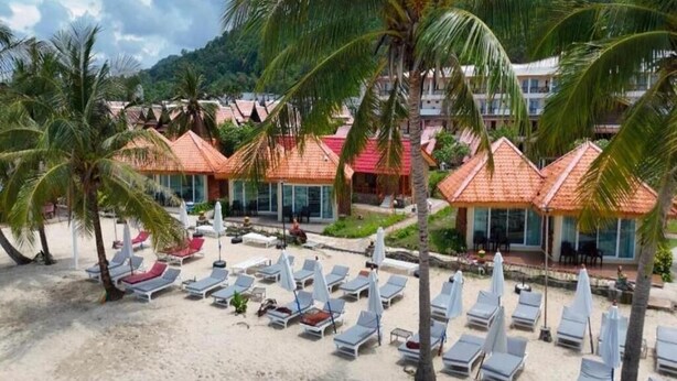 A beach resort with sun loungers, palm trees, and buildings with red roofs. - beachfront villa (Ko Chang)