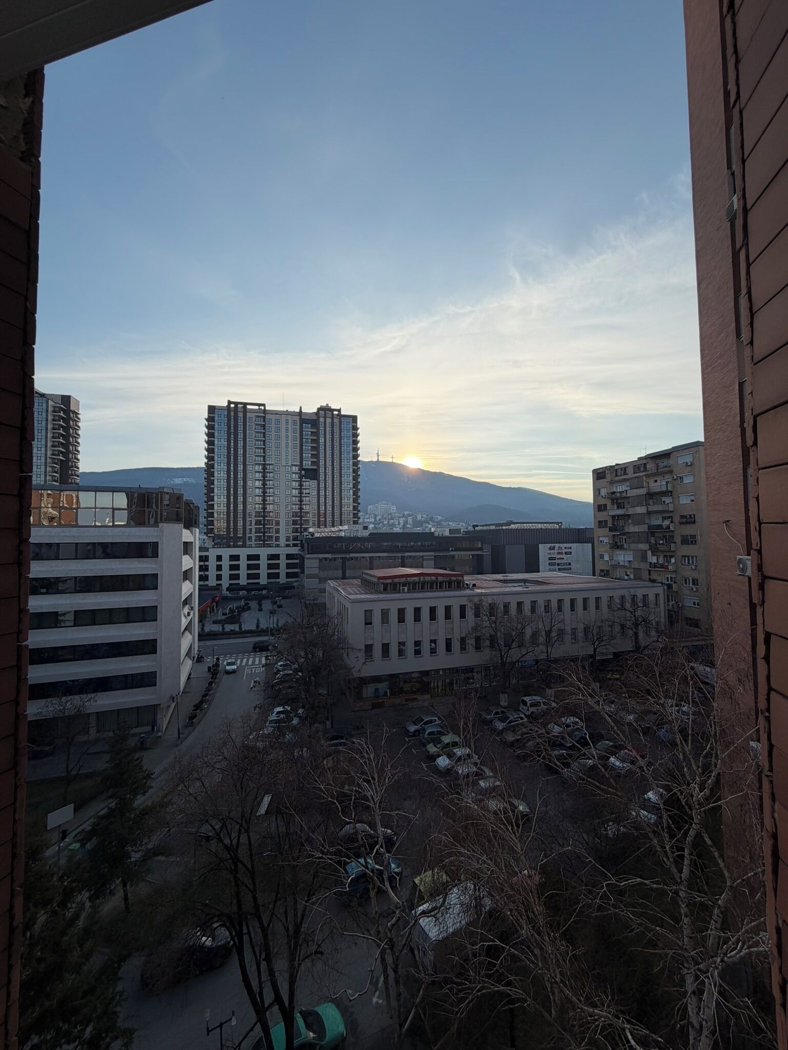 Un paisaje urbano con rascacielos, un estacionamiento y cielo despejado.