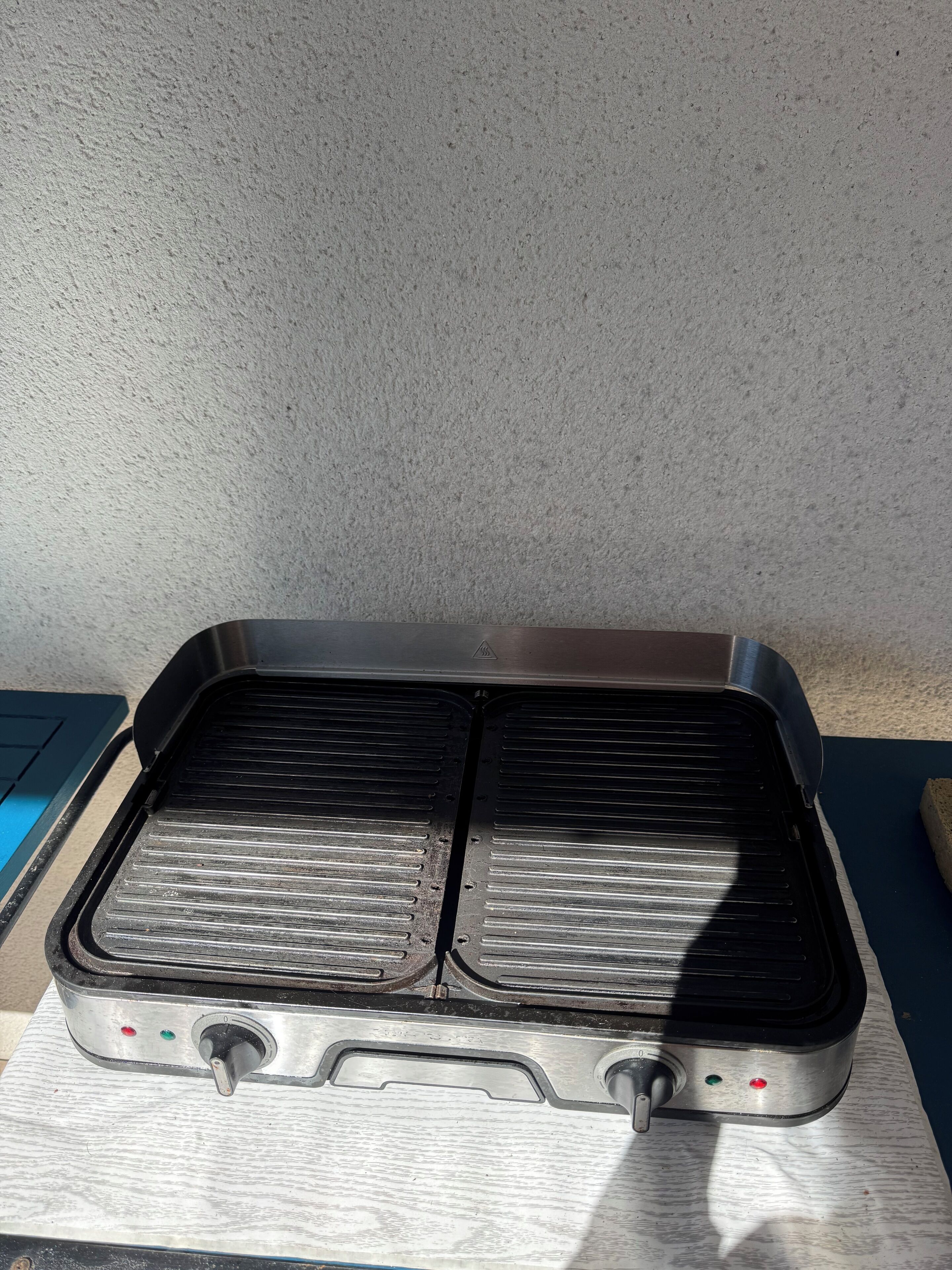 En portabel grill med två grillytor och justeringsknappar.