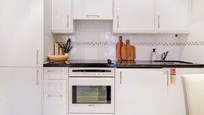 A modern kitchen with white cabinets, a black countertop, a built-in oven, and a sink. - Stylish Mayfair Escape off Piccadilly (London)