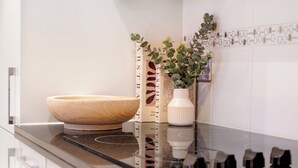 A kitchen with a wooden bowl, a white vase with green plants, and a tiled backsplash. - Stylish Mayfair Escape off Piccadilly (London)