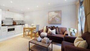 A modern living room with a sofa, coffee table, and dining area. - Stylish Mayfair Escape off Piccadilly (London)