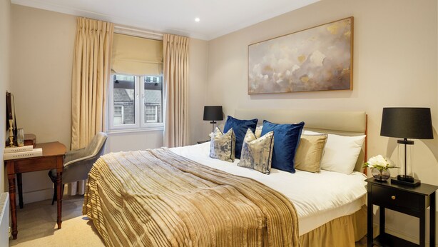 A hotel room with a large bed, a desk, and a window with curtains. - Stylish Mayfair Escape off Piccadilly (London)