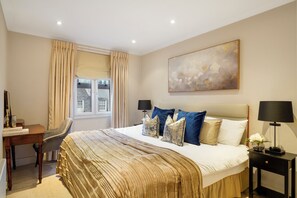 A hotel room with a large bed, a desk, and a window with curtains. - Stylish Mayfair Escape off Piccadilly (London)