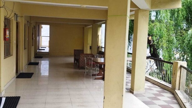 Un pasillo amplio con suelo de baldosas, un área exterior a cuadros y vistas al verdor.