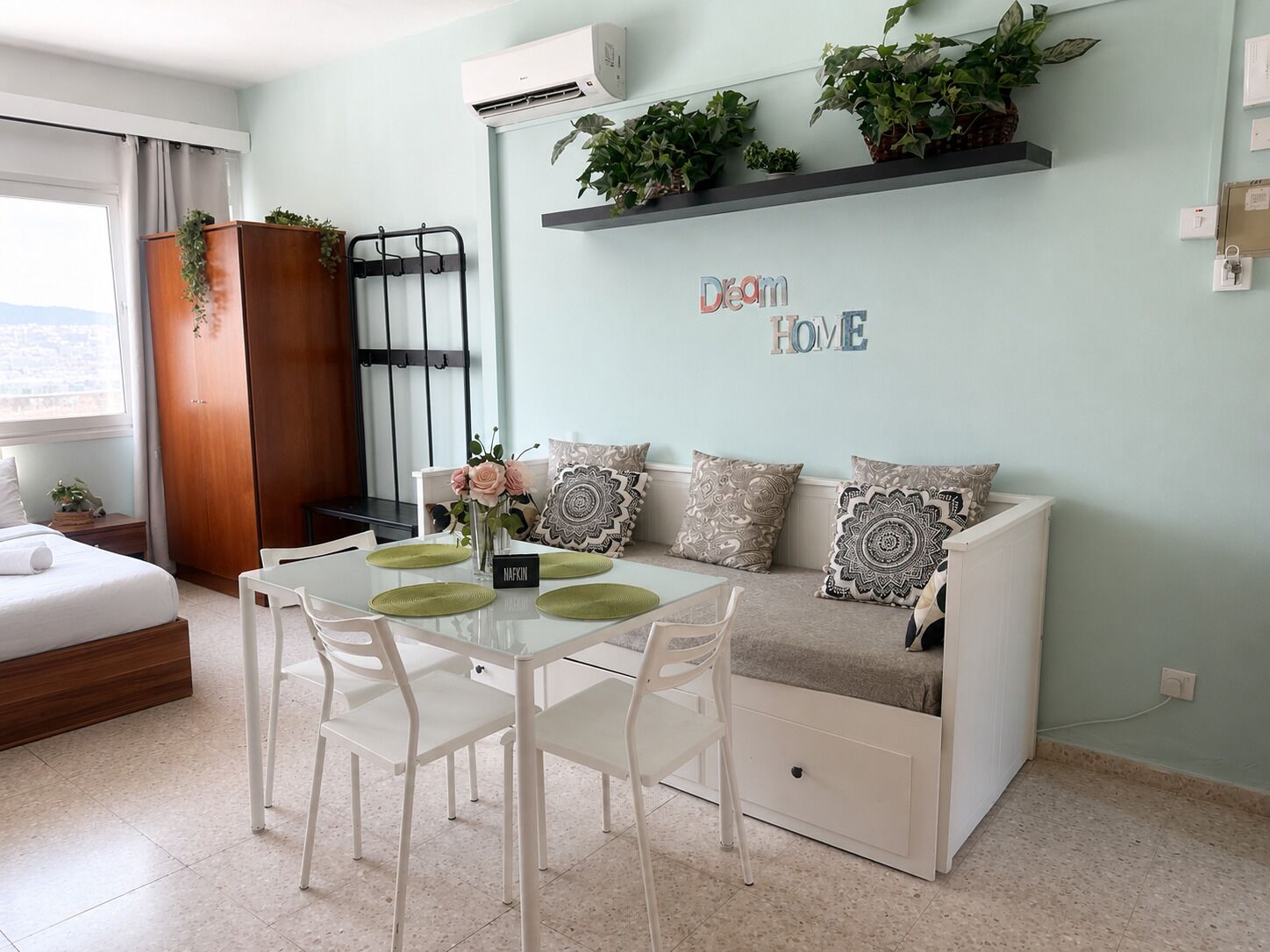 Ein modernes Wohnzimmer mit einer Couch, einem Esstisch, Stühlen und einem kleinen Pflanzenregal.