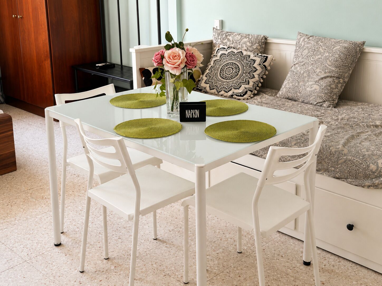 A dining table with two chairs, a vase with flowers, and a placemat with the text 'NAPKIN'.