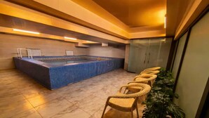A spa area with a tiled pool, lounge chairs, and a potted plant. - BlueShore International hotel (Tashkent)