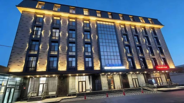 A modern hotel with a prominent glass facade, multiple floors, and a well-lit entrance. - BlueShore International hotel (Tashkent)