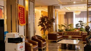 A hotel lobby with leather sofas, a chandelier, a reception desk, and a large plant. - BlueShore International hotel (Tashkent)