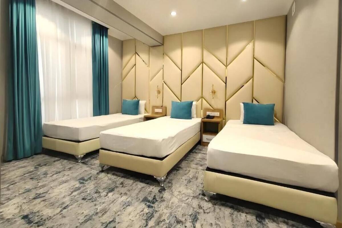 Ein Hotelzimmer mit drei Betten, einem Marmorboden und einer Zierwandverkleidung.