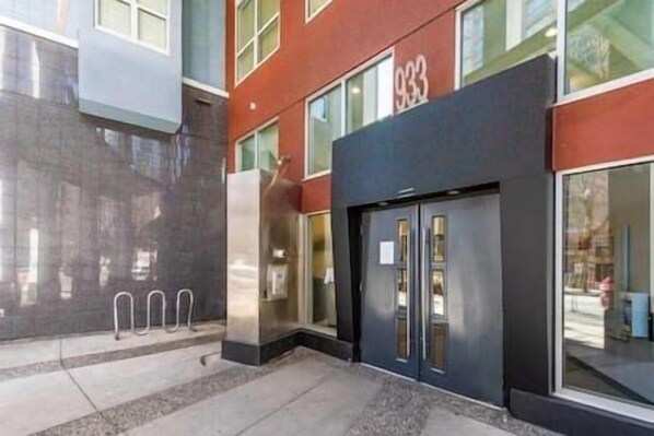 A building with a large glass entrance, a visible number '933' on the facade, and a metal structure to the left. - Urban Loft Oasis • Green Patio • Free Parking (Vancouver)