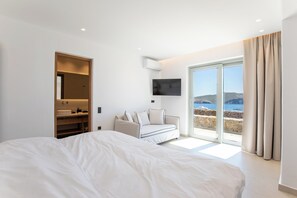 Une chambre avec un lit, un canapé, une télévision et une vue sur la mer.