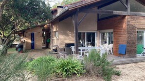 A two-story house with a patio area, a blue door, and a wooden deck. - Vacation home Hossegor 100m from the lake - 600m from the market! (Soorts-Hossegor)
