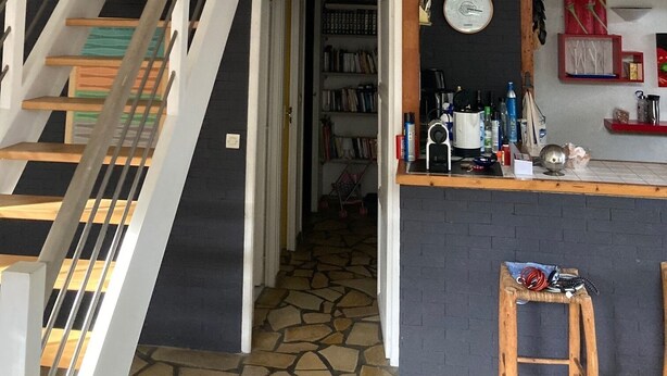 A multi-level interior with a staircase, a kitchen area with a clock, and a bookshelf. - Vacation home Hossegor 100m from the lake - 600m from the market! (Soorts-Hossegor)