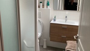 A modern bathroom with a skylight, a toilet, a sink with a mirror, and a small stool. - Vacation home Hossegor 100m from the lake - 600m from the market! (Soorts-Hossegor)