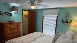 A bedroom with a bed, dresser, ceiling fan, and a sign that reads 'BEACH'. - Cute Bungalow in Cherry Grove, SC. Just a Chip Shot from ocean & beach access! (North Myrtle Beach)