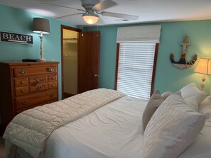 A bedroom with a bed, dresser, ceiling fan, and a sign that reads 'BEACH'. - Cute Bungalow in Cherry Grove, SC. Just a Chip Shot from ocean & beach access! (North Myrtle Beach)