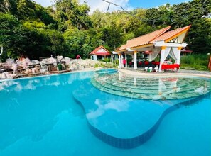 A swimming pool with a circular design, surrounded by a covered seating area with red and white colors. - family villa (Ko Chang)
