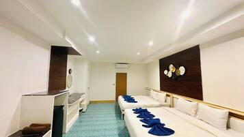 A hotel room with two beds, a desk, and a shower area.