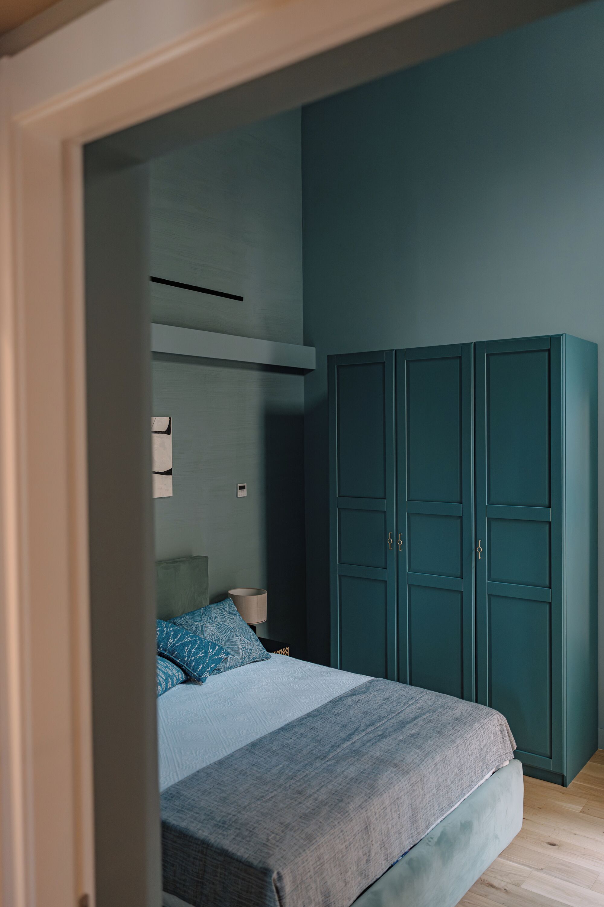 A bedroom with a bed, a wardrobe, and a nightstand.