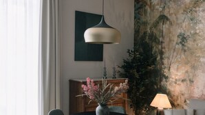 Ein stilvoller Essbereich mit einem runden Tisch, vier Stühlen, einer Blumenvase und einer Hängeleuchte.
