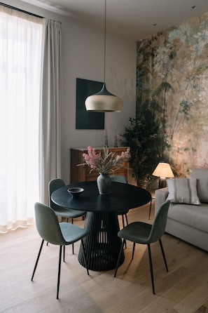 A modern dining area with a round table, four chairs, a vase with flowers, and a hanging light fixture. - Silva Apartment (Catania)