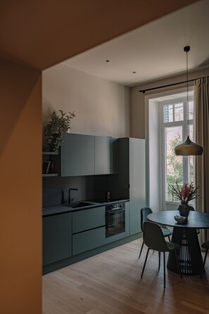 A modern kitchen with dark cabinets, a round dining table, and a hanging light fixture. - Silva Apartment (Catania)