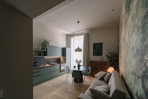 A modern kitchen with a dining area, a sofa, and a large window with curtains. - Silva Apartment (Catania)