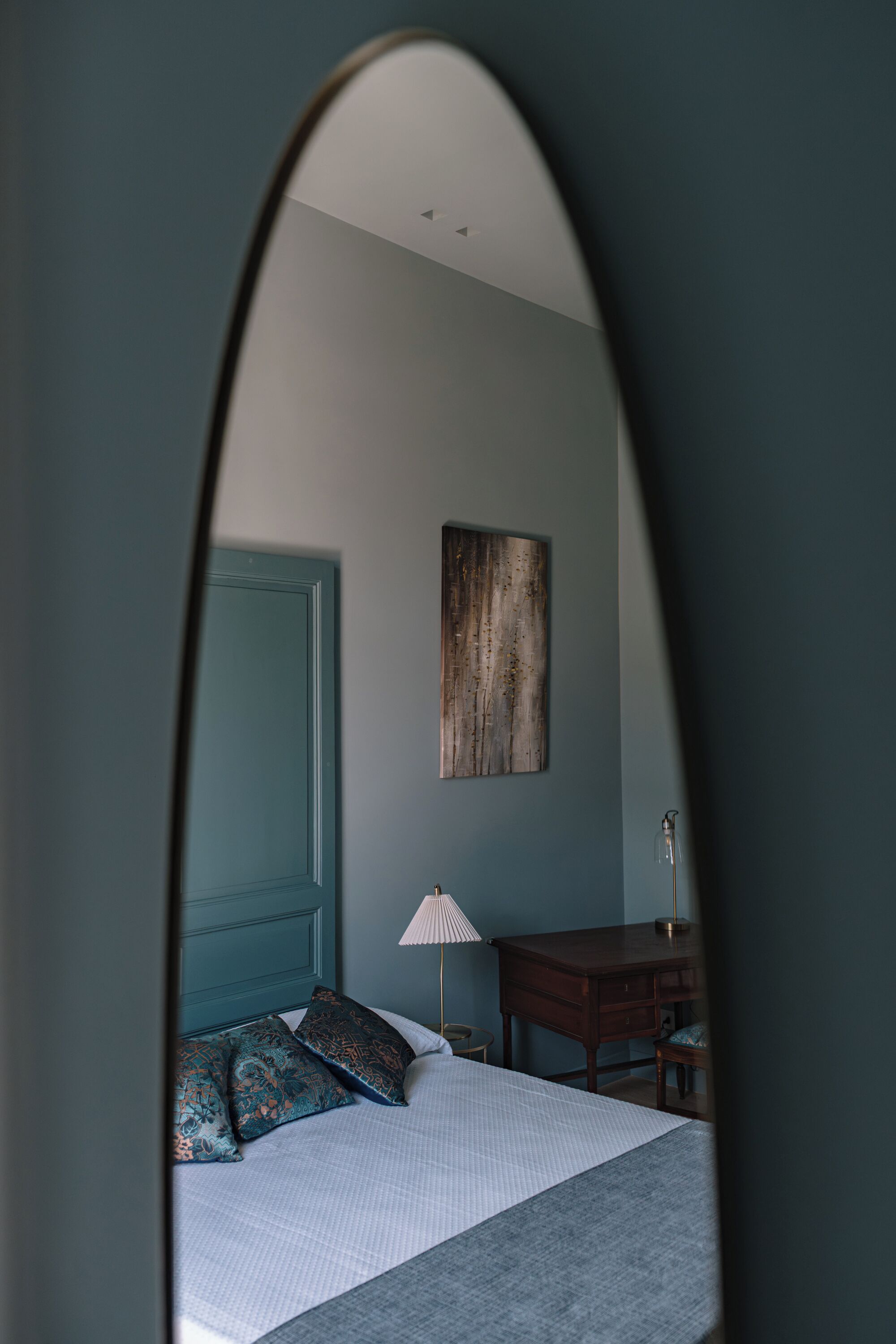 A bedroom with a bed, a desk, and a lamp.