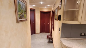 A hallway with wooden doors, framed artwork on the walls, and a tiled floor. - Gran Paradis Aprica - Casa Giulia (Corteno Golgi)