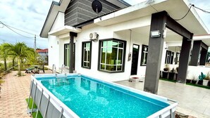 Ein modernes Haus mit rechteckigem Pool, einer überdachten Terrasse und Blick auf die Umgebung.