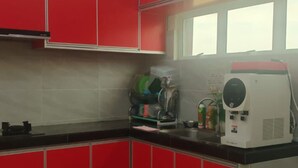 Eine Küche mit roten Schränken, einer schwarzen Arbeitsplatte, einem Fenster und einer Kaffeemaschine.